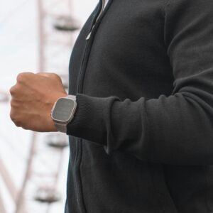 A modern man admiring his smartwatch with the iconic London Eye in the background, symbolizing technology and travel.