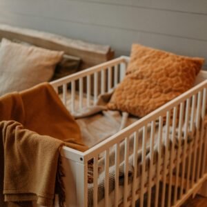 A warm, inviting nursery displaying a stylish crib adorned with textured pillows and a plush blanket.